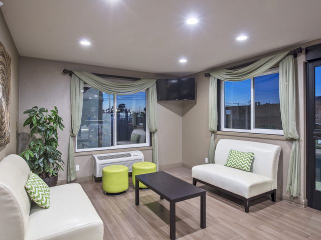 A hotel lobby with two white sofas, a coffee table, and a TV on the wall.