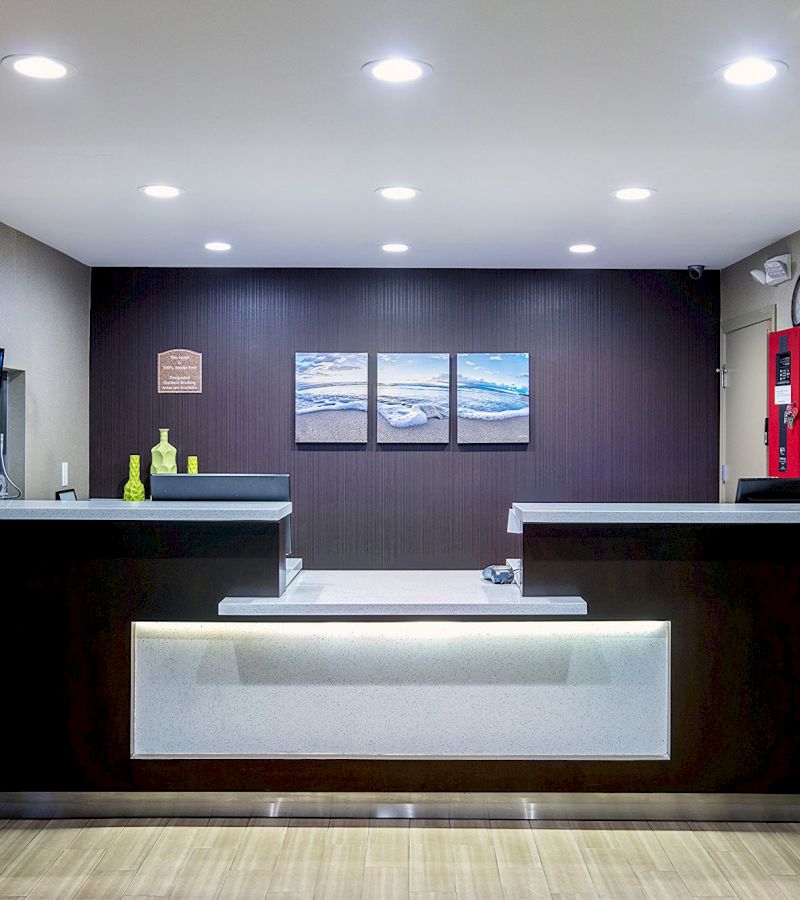 A hotel lobby with a modern front desk and artwork on the wall.